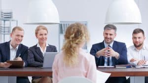 Candidate confiante expliquant sereinement son parcours professionnel lors d'un entretien d'embauche face à des recruteurs
