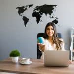 Entretien d'embauche avec un cabinet de recrutement : comment le réussir ? Femme souriante en entretien cabinet de recrutement assise à son bureau avec un ordinateur portable
